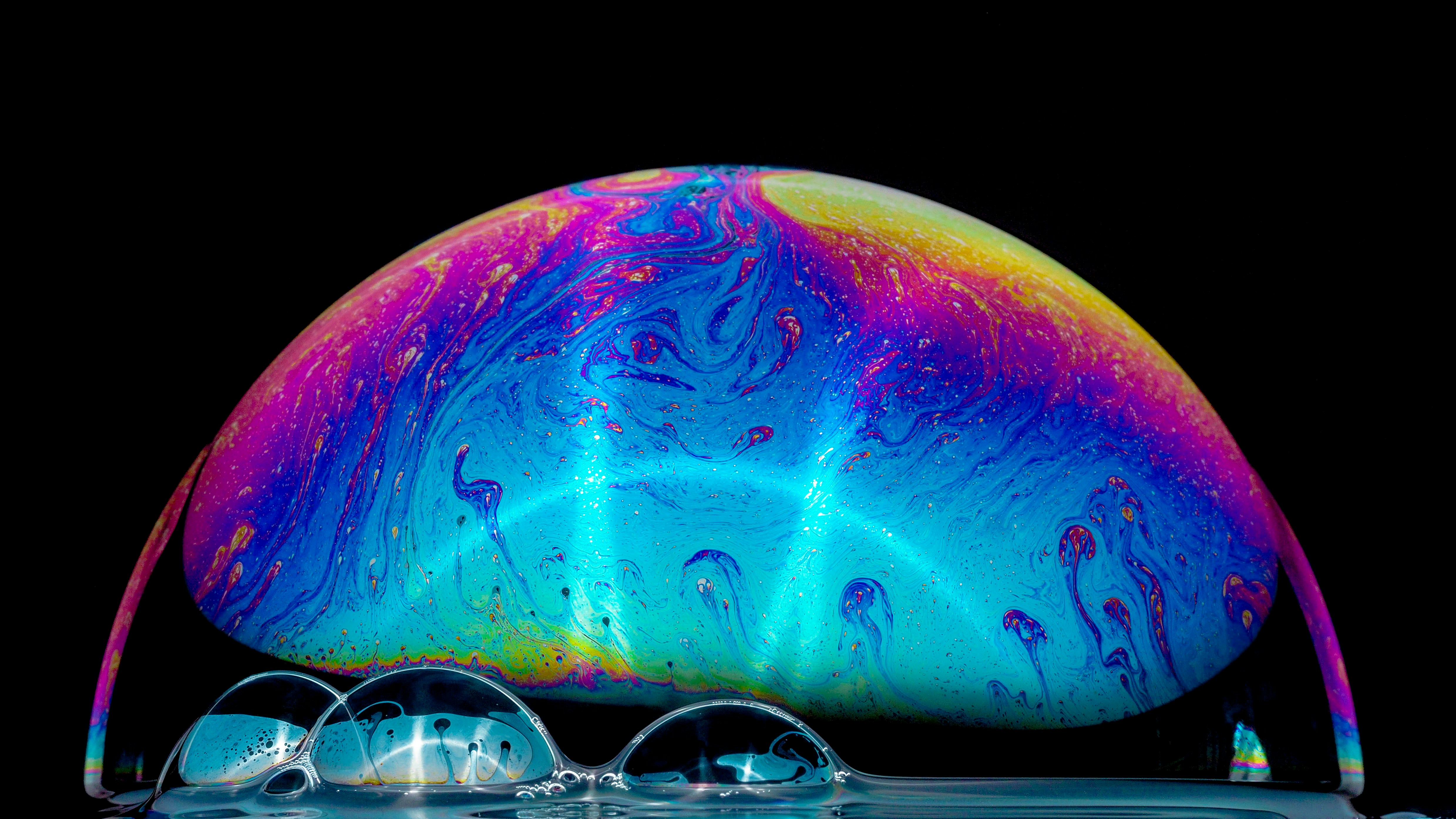 Close-up of a single soap bubble reflecting light with a colourful iridescent surface.