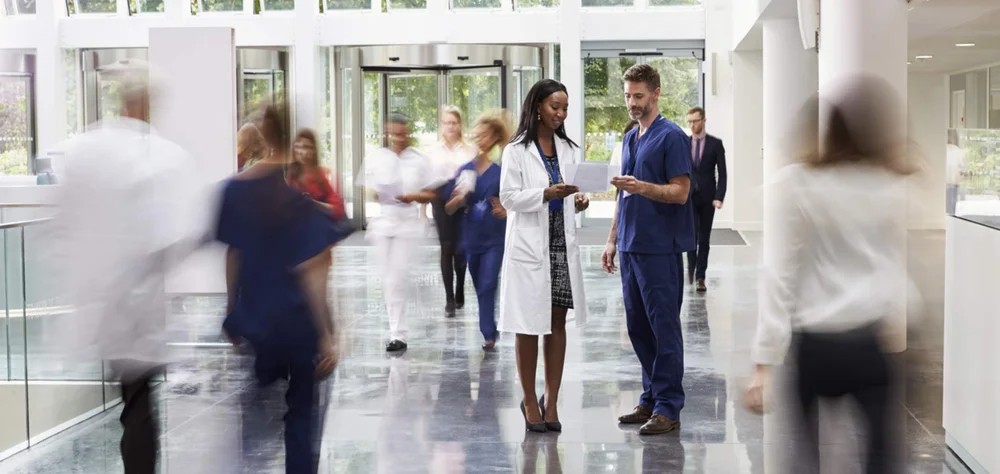 Two medical professionals standing in a hospital setting, representing healthcare teamwork.
