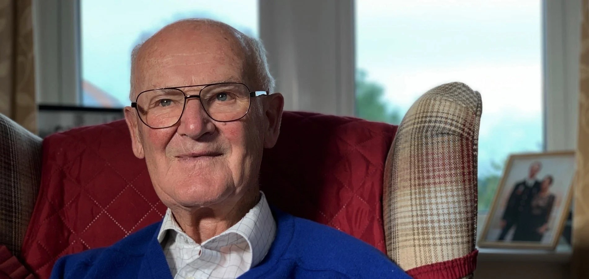 Older man sitting on a chair indoors in a calm, everyday setting.