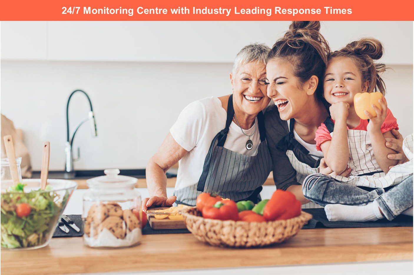 Three generations of a family smiling together in a kitchen, representing independent living and 24/7 monitoring support for older adults.