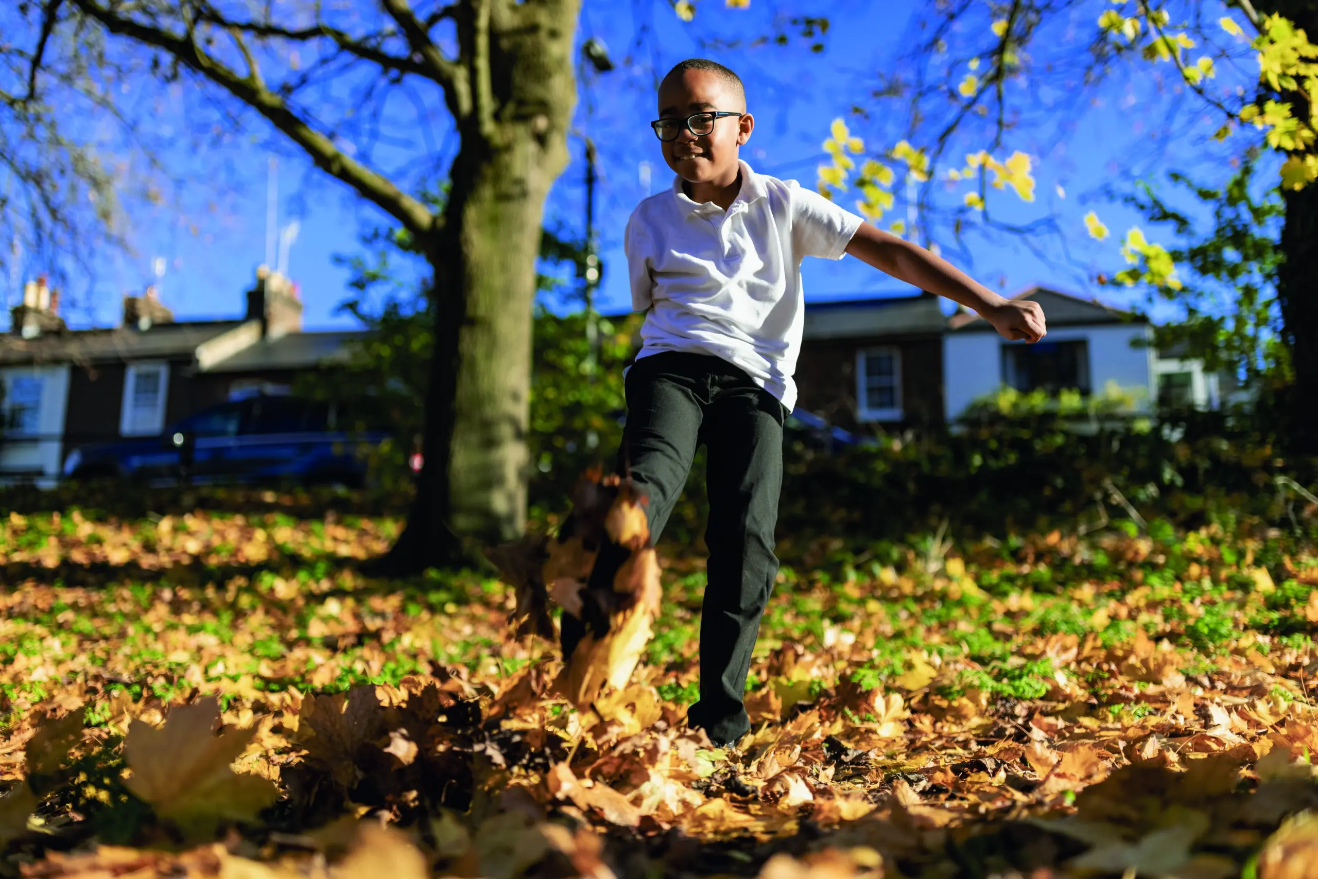 A child kicking a fallen yellow leaf while playing outdoors.