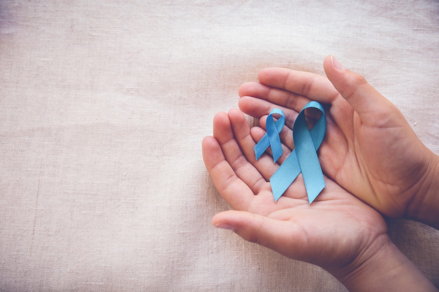 An image of hands holder the blue ribbon of prostate cancer awareness.