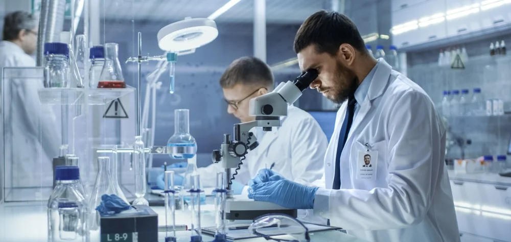 Scientist in a laboratory testing samples and looking through a microscope.